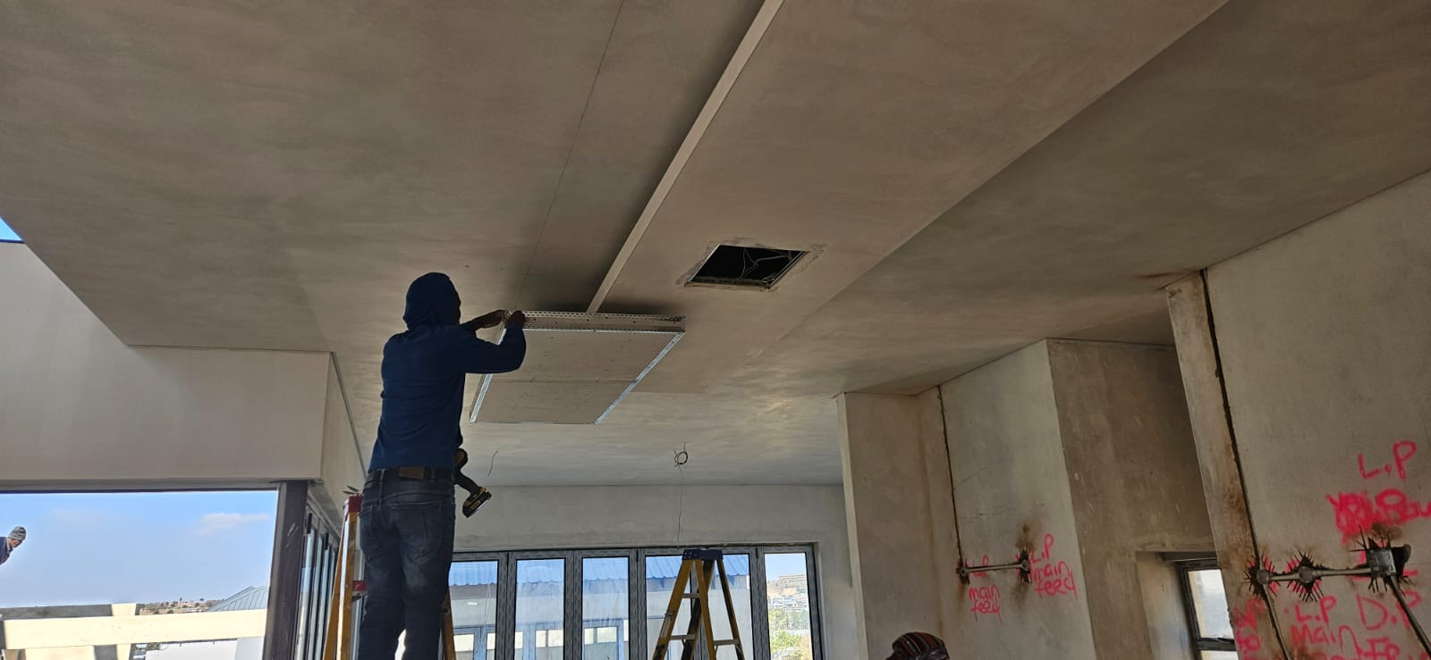 Builders finishing exterior plasterwork on a double-storey home